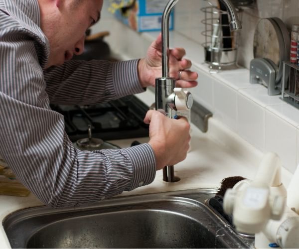 Installateur repariert einen Wasserhahn in der Küche — Sanitär-Notdienst vor Ort