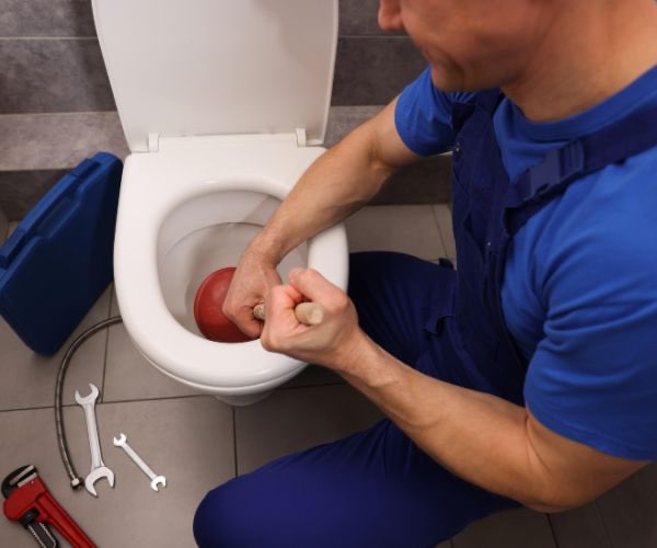 Sanitärtechniker beseitigt Verstopfung in der Toilette mit Saugglocke