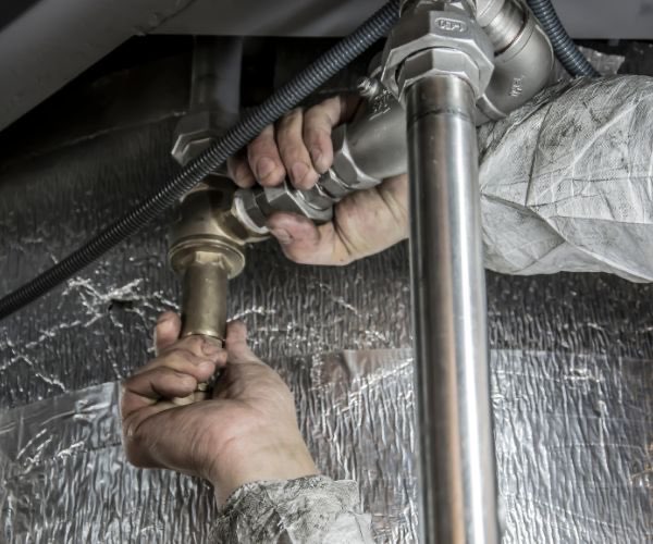 Hände verbinden Boiler-Anschlüsse und Kupferrohre — Boilerreparatur und Installation